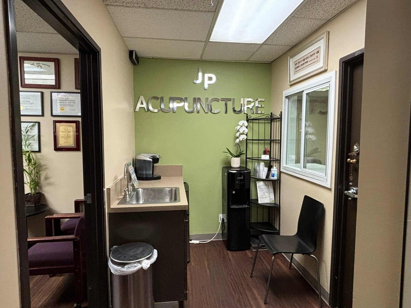 The waiting area at JP Acupuncture & Wellness, with the clinic's logo on the wall and comfortable seating